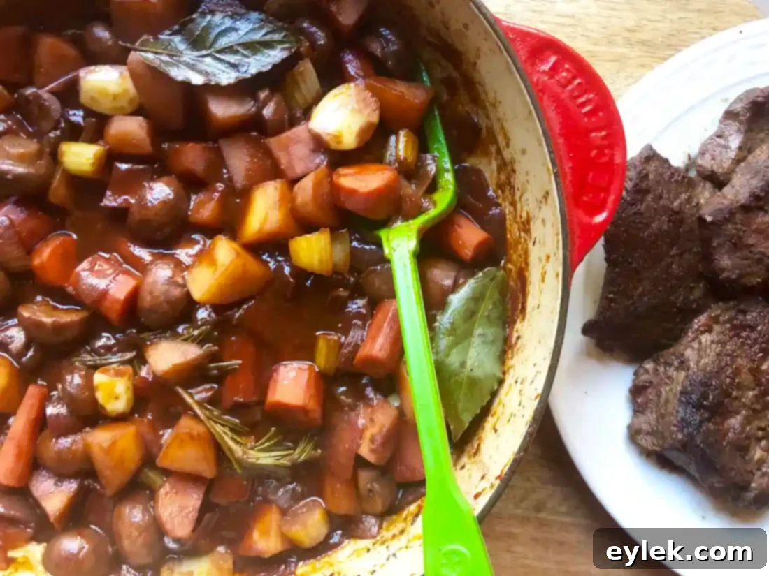 Seared beef returned to the pot with vegetables and broth, ready for braising