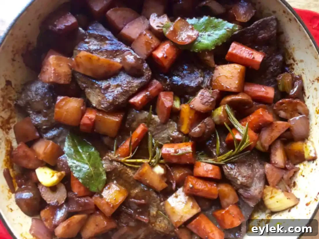 Braised beef stew simmering in a covered Dutch oven in the oven