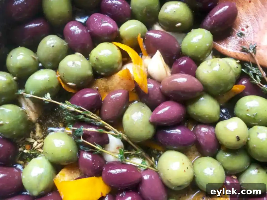 A close-up of the warm marinated olives, highlighting the rich olive oil and fragrant spices.