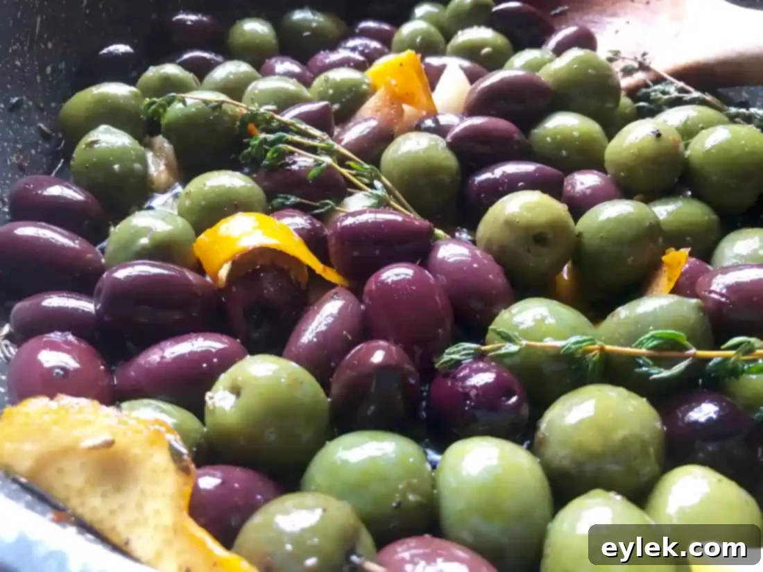 A bowl of Ina Garten's Warm Marinated Olives, ready for serving with a small dish for pits.