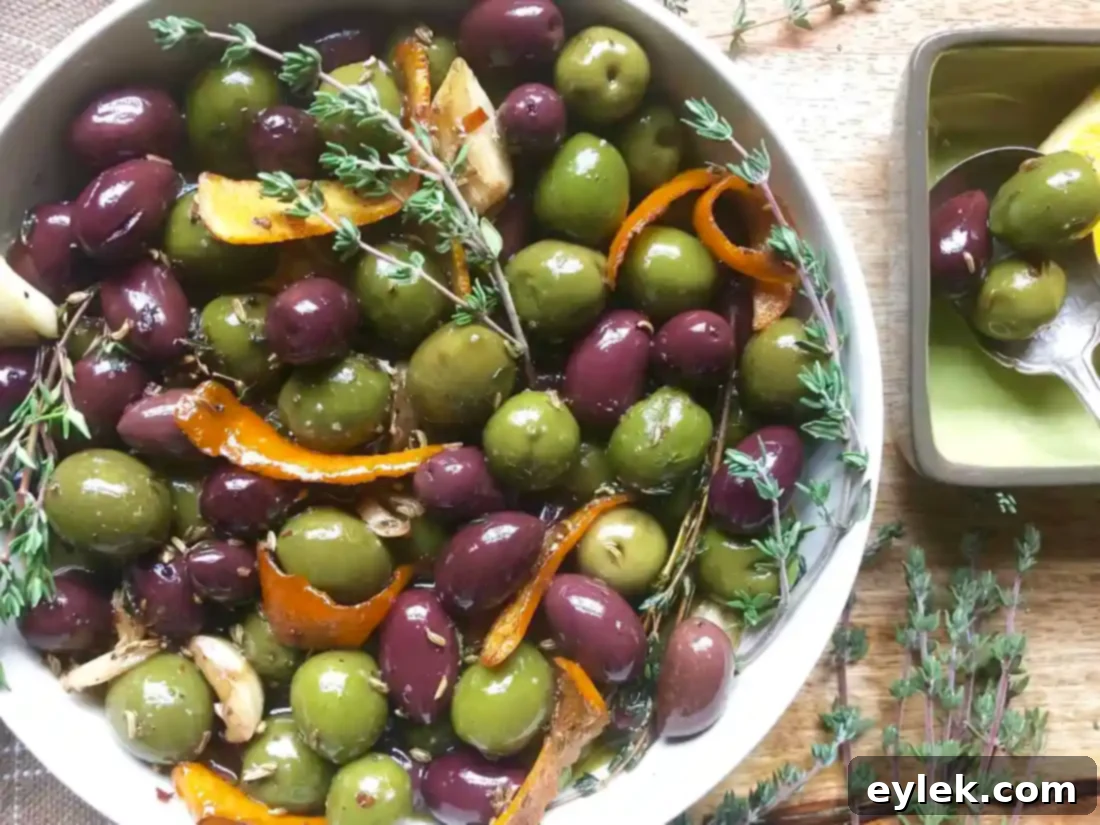 An elegantly styled serving of Ina Garten's Warm Marinated Olives with bread and cheese.