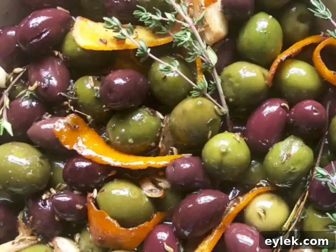A selection of cheeses and crackers arranged around a bowl of warm marinated olives, perfect for a gathering.
