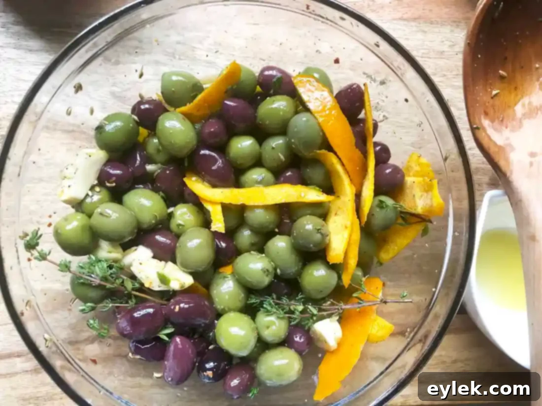 Marinated olives, herbs, and garlic heating in a sauté pan on the stovetop.