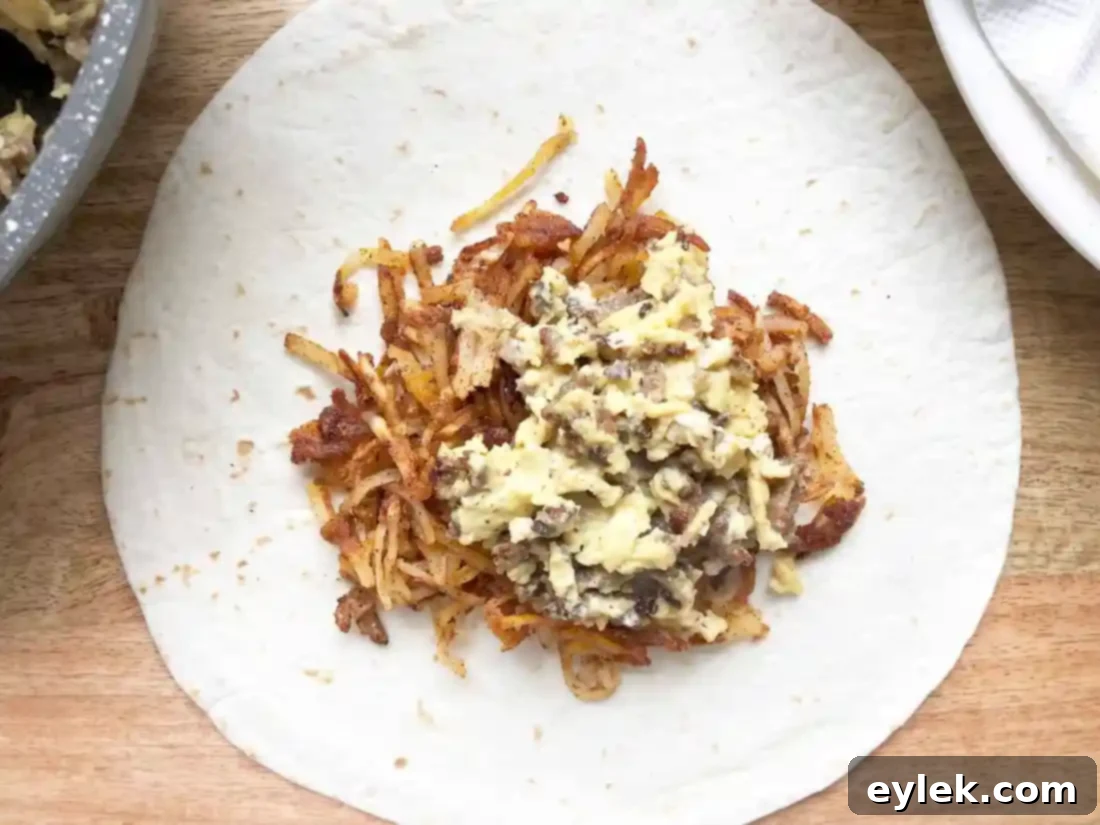 Layering hash browns, egg, sausage, and cheese in a tortilla