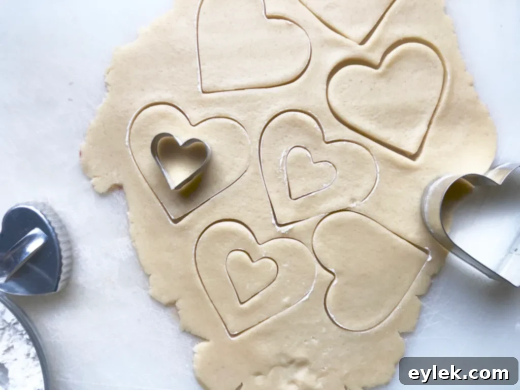 Dough being cut into heart shapes for patchwork cookies