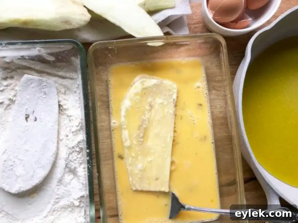 Eggplant slices coated in flour and egg, ready for frying