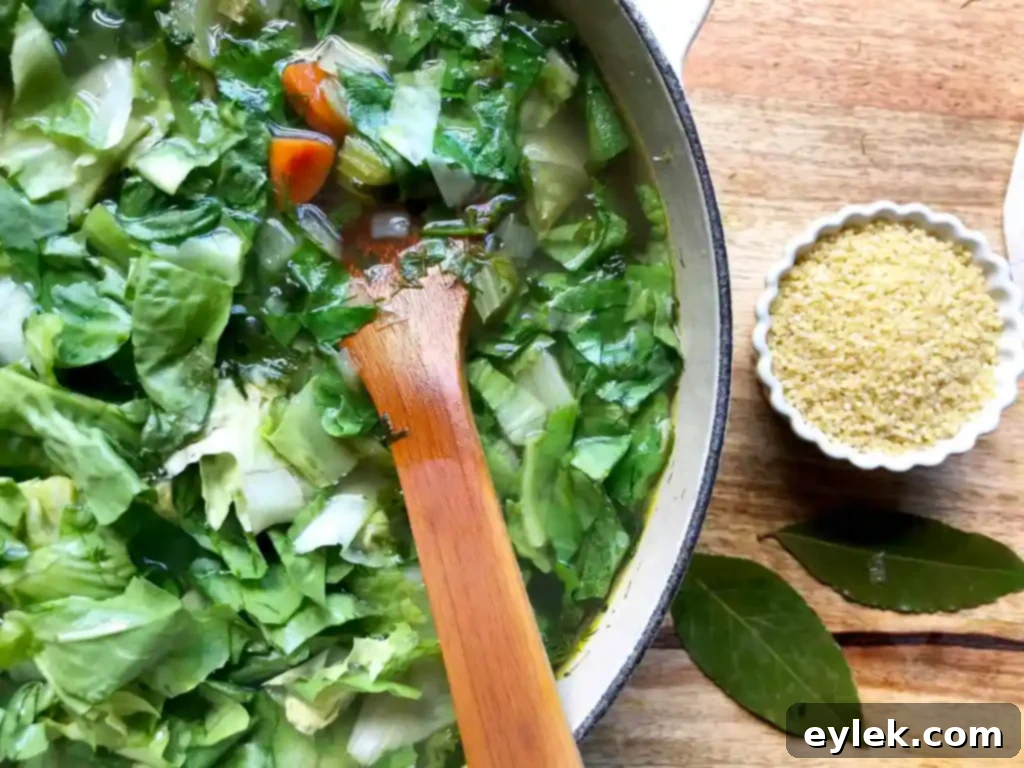Shredded rotisserie chicken breast being gently stirred into the simmering chicken escarole soup.