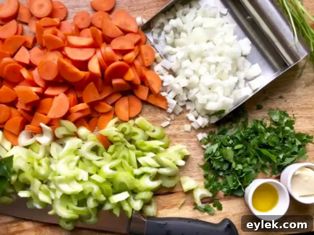 Preparing the aromatic vegetables for Chicken Escarole Soup, showing diced carrots, celery, and onion.
