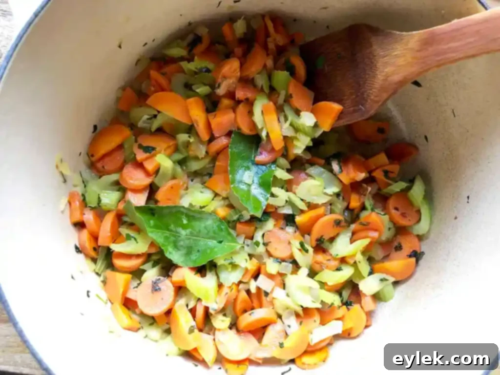 Sautéed carrots, celery, and onion cooking in a large pot for the chicken escarole soup.