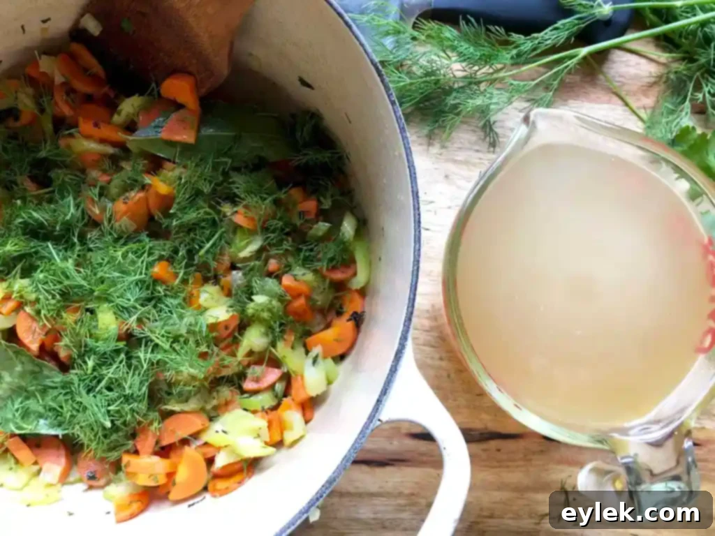 Chicken broth simmering with sautéed vegetables and fresh dill for the escarole soup.