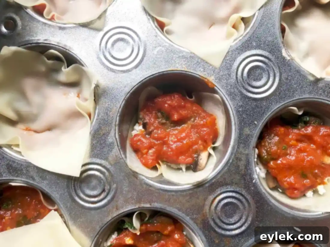The veggie lasagna cups fully assembled in the muffin tin, ready to be baked.