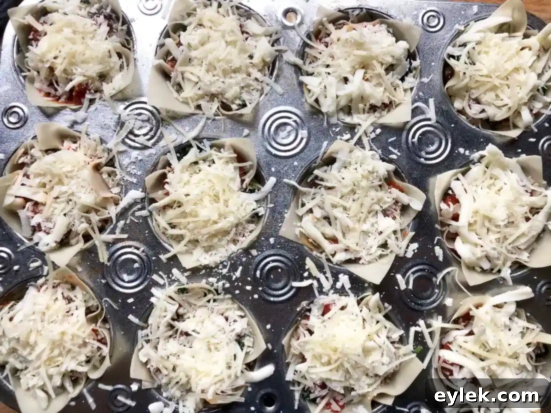 Marinara sauce being spooned over the top layer of cheese and vegetables in the lasagna cups.