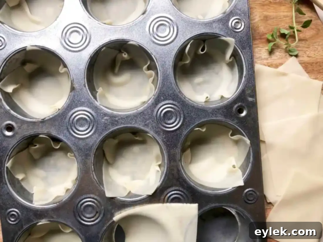 Muffin tin lined with wonton wrappers, ready for filling to create veggie lasagna cups.