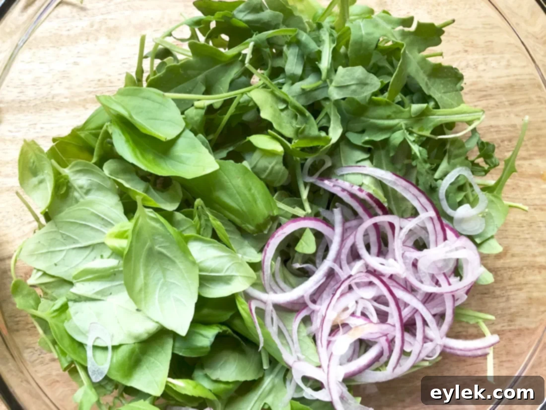 Mixing the salad greens with thinly sliced red onion