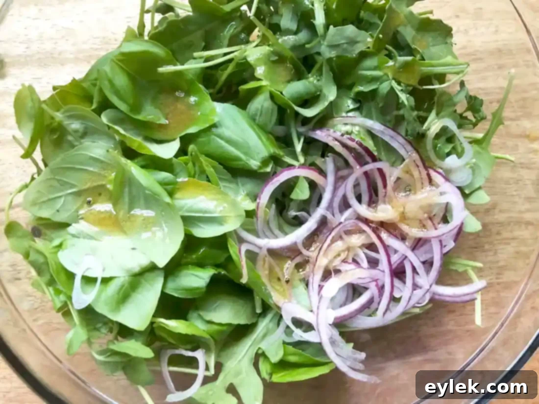 Tossing basil, arugula, and onion with vinaigrette