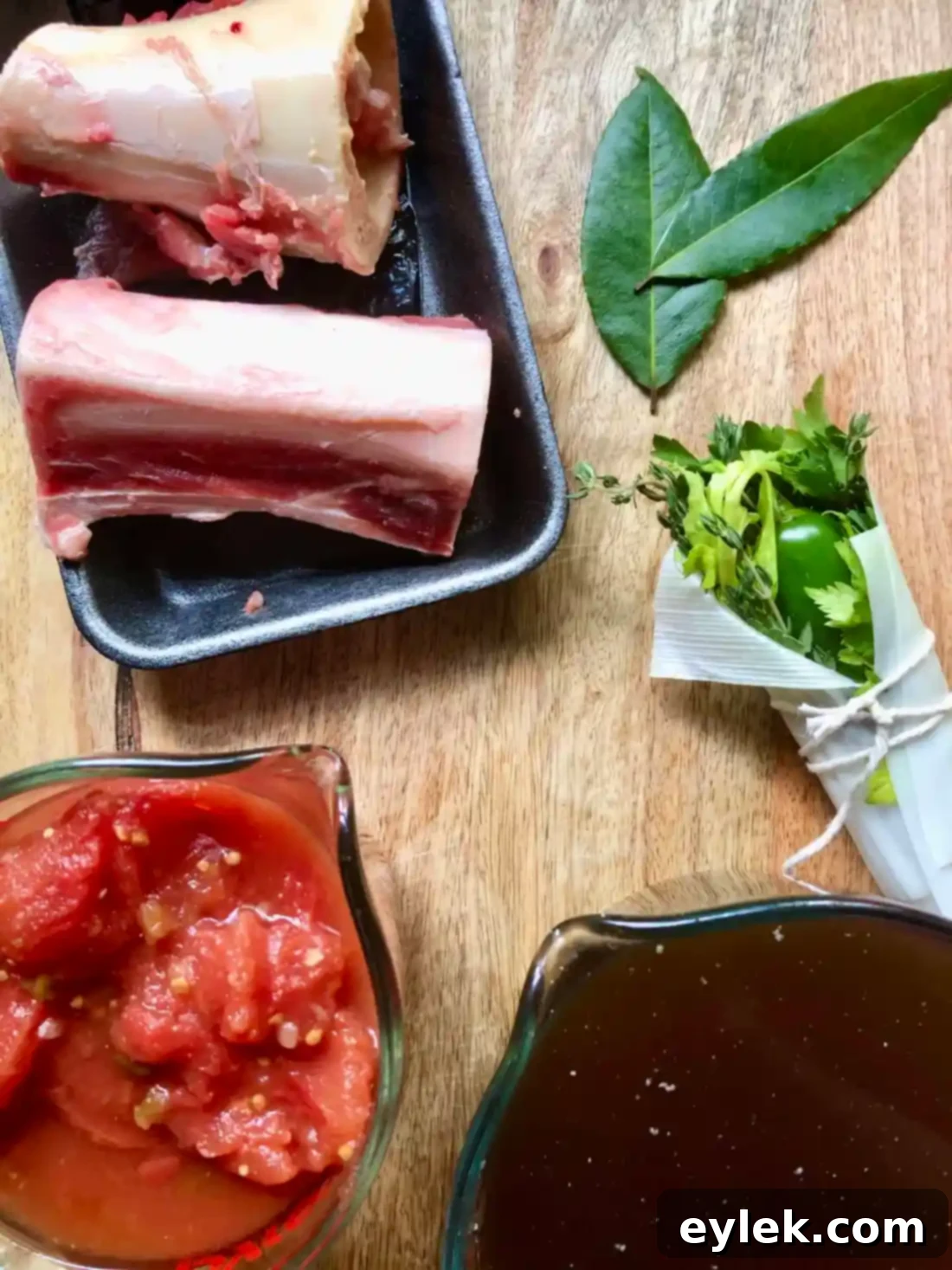 Ingredients for beef barley soup including broth, tomatoes, soup bones, pot herb, and bay leaves