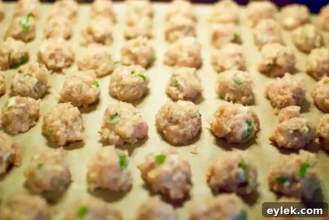 Raw meatballs on a baking sheet, ready for the oven