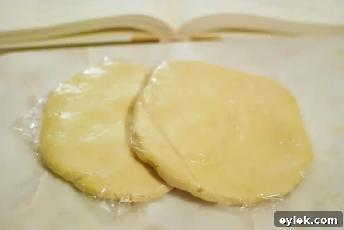 Raw Almontina cookie dough discs wrapped in plastic, ready for chilling or freezing.