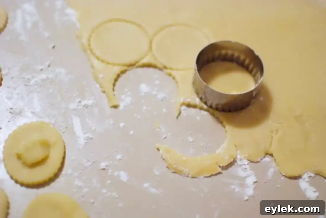 Raw Almontina cookie rounds with almond filling being assembled on a baking sheet.