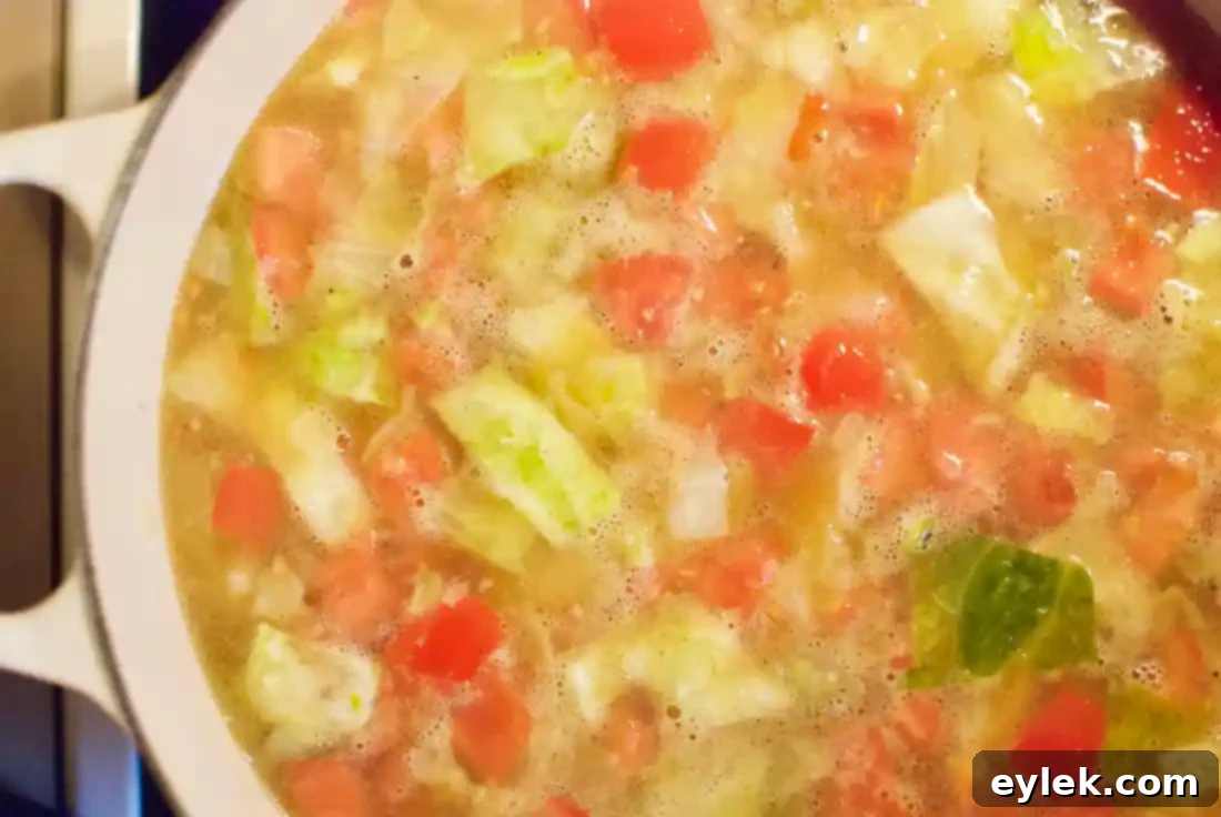 A close-up of the minestrone being pureed with an immersion blender to create a thicker, richer consistency.