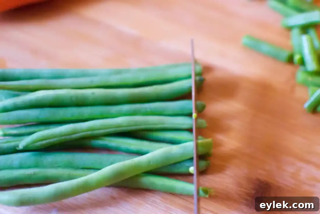 Fresh green beans meticulously lined up on a cutting board, ready for trimming for the soup.