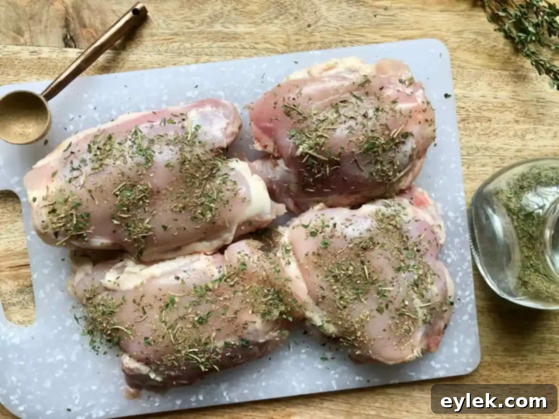 Raw chicken thighs seasoned with Herbes de Provence, ready for cooking