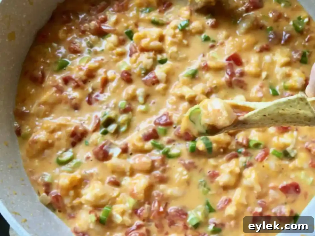 The ultimate party appetizer: a generous serving of homemade queso dip with shrimp, garnished and ready for dipping.