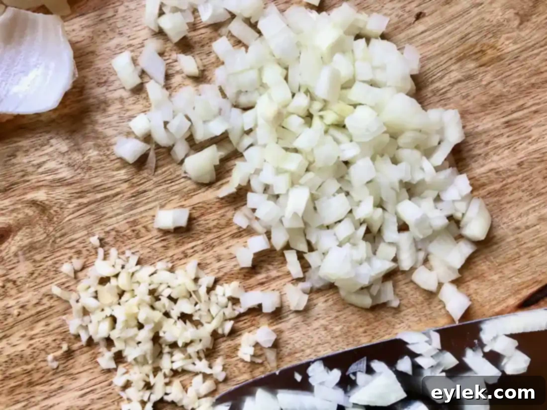 Preparing ingredients for the homemade queso dip with shrimp, including freshly chopped onions and garlic.