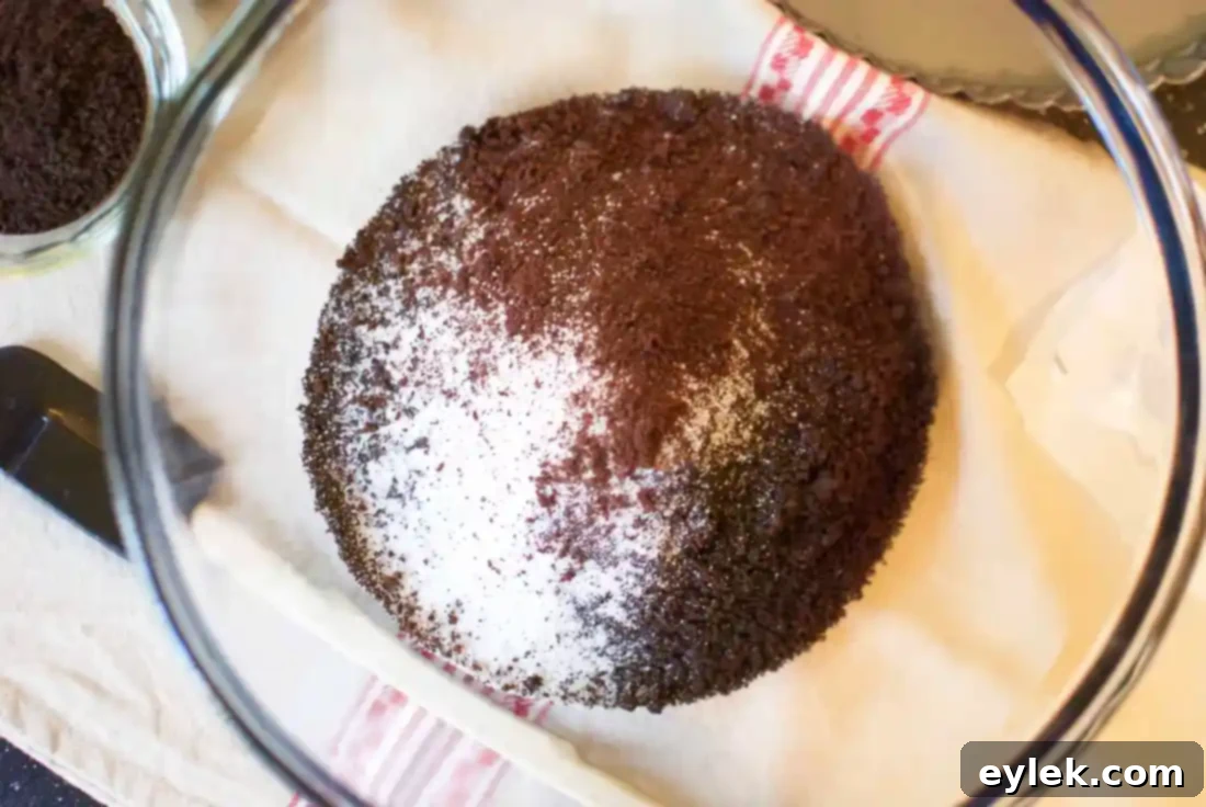 Mixed chocolate cookie crumbs with melted butter and espresso powder, ready to be pressed into the tart pan.