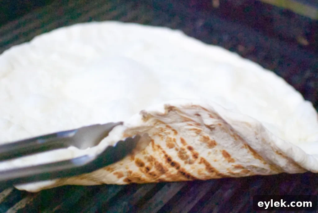 Pizza dough being placed on a hot grill for the first side