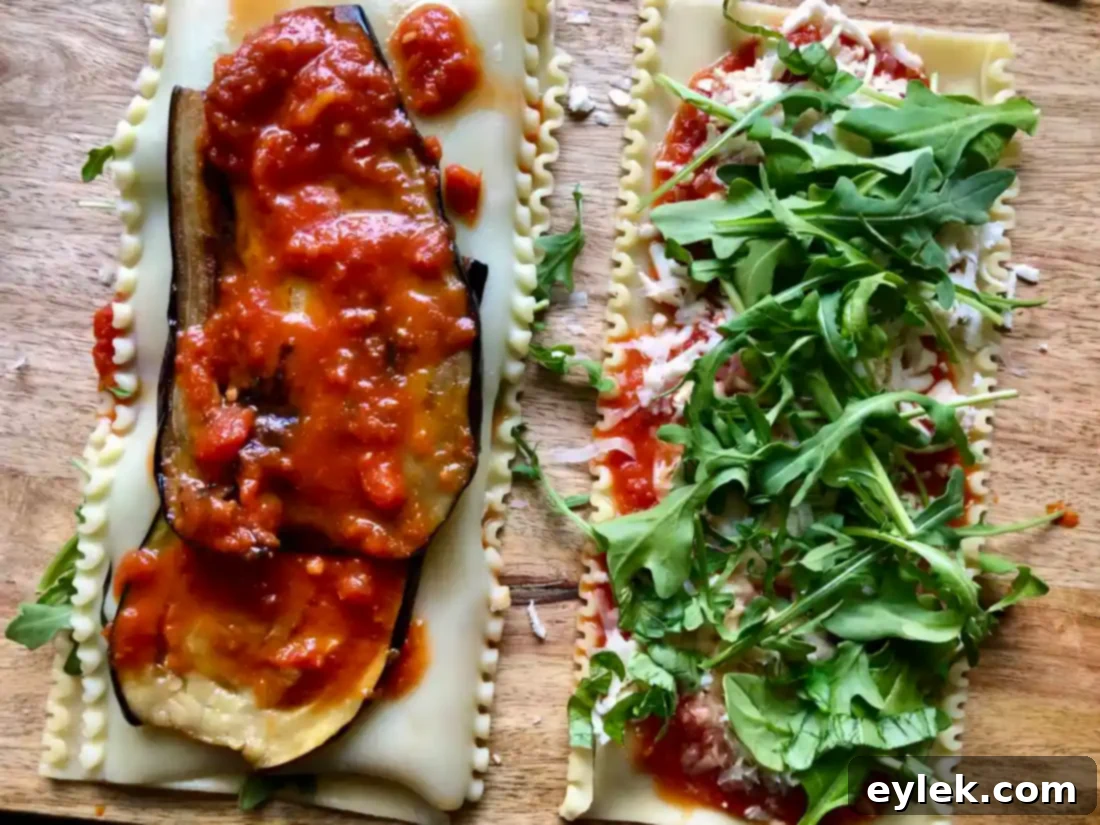 Lasagna noodle with layers of marinara sauce, Parmesan, mozzarella, arugula, and basil, precisely prepared for the next step of layering before rolling into spirals.