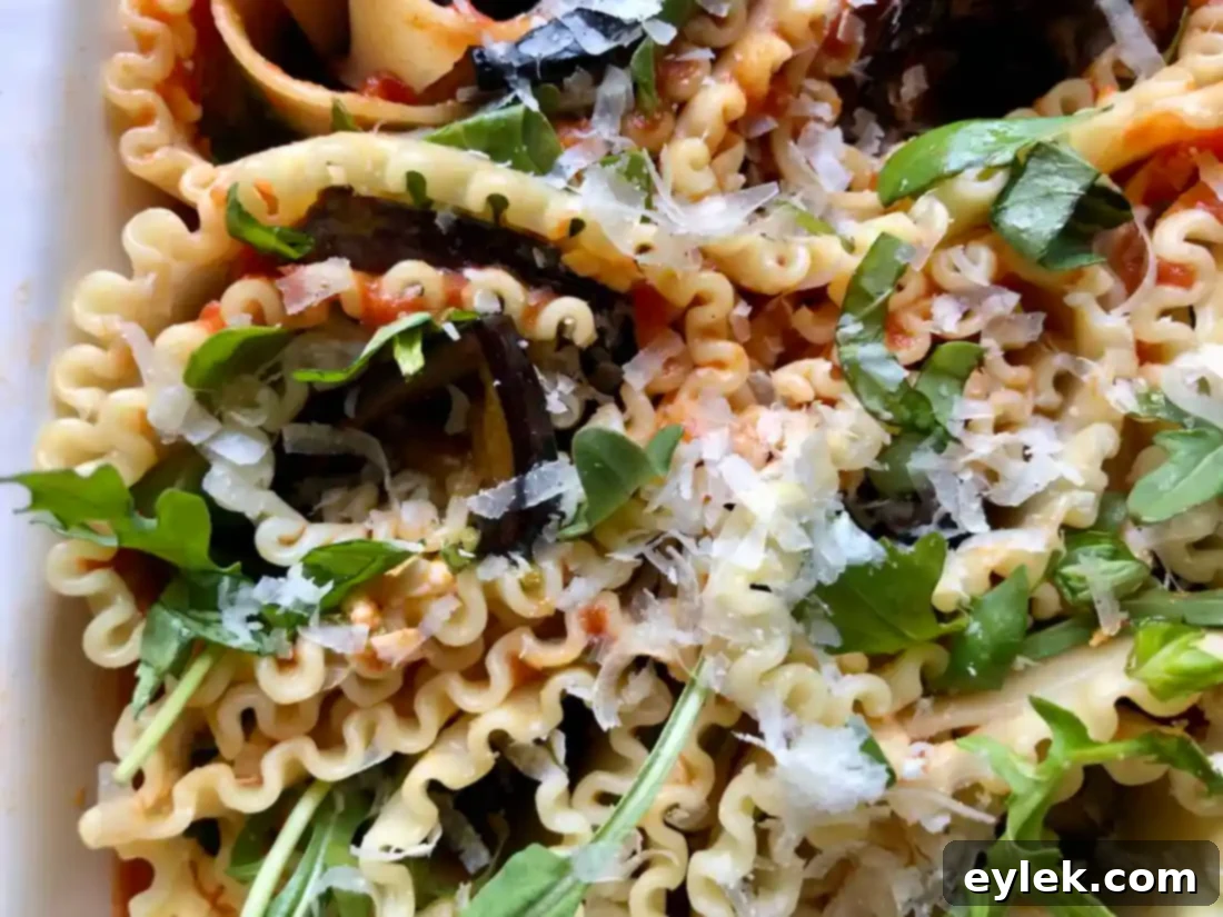 Close-up of Sautéed Eggplant Lasagna Spirals meticulously arranged in a baking dish before baking, highlighting the layered eggplant, cheese, and pasta.