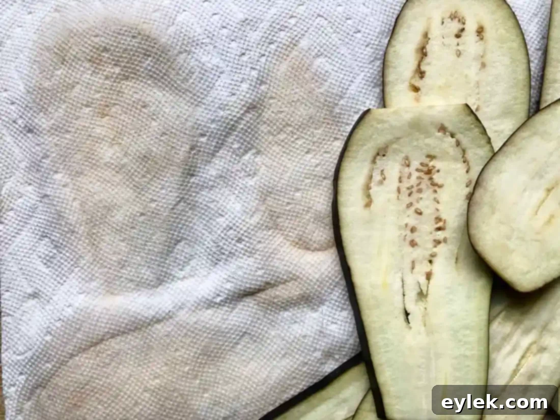 A stack of paper towels saturated with moisture from salted eggplant slices, demonstrating the effectiveness of the sweating process.