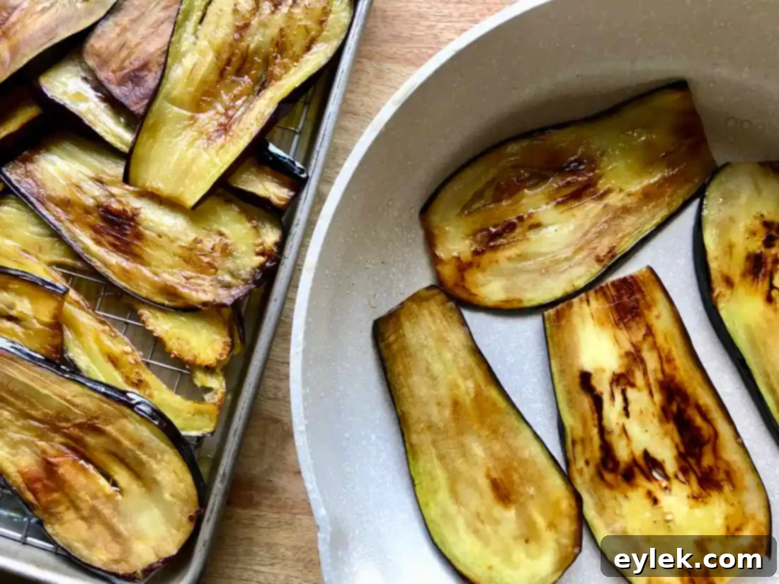 Close-up view of a perfectly cooked, golden-brown eggplant slice being removed from a skillet, showing its readiness for the lasagna spirals.