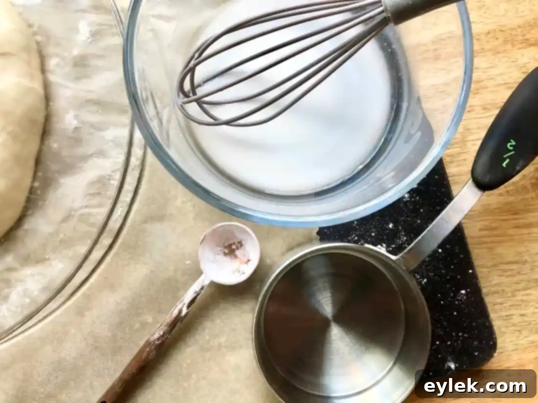 Preparing the no-knead olive bread for baking with scoring and cornstarch wash