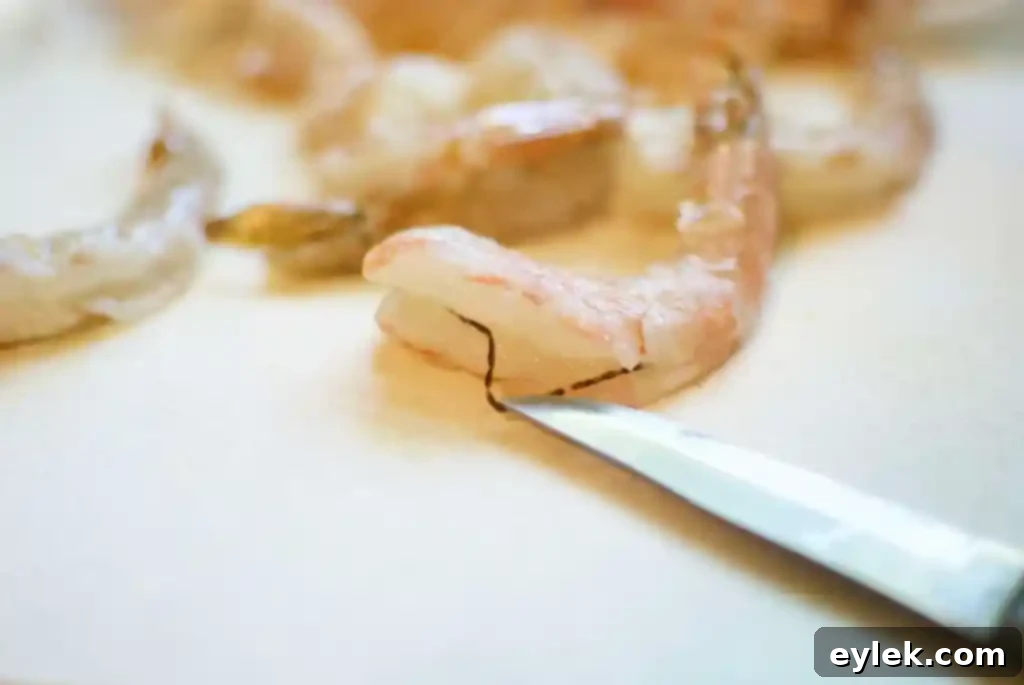 Close-up of a hand deveining shrimp using kitchen shears