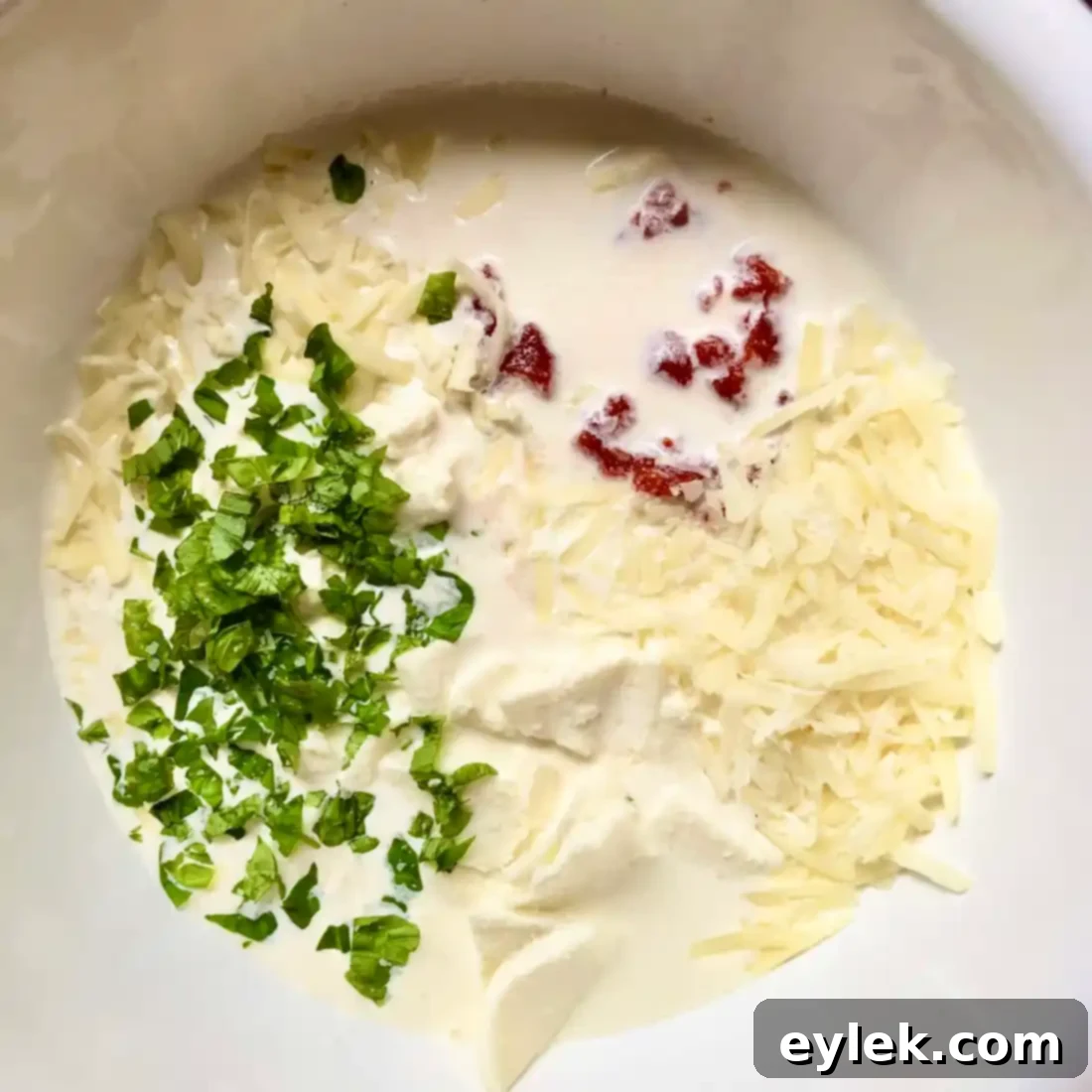 Penne with Tomato, Cream & Five Cheeses, being mixed in a large bowl before baking.