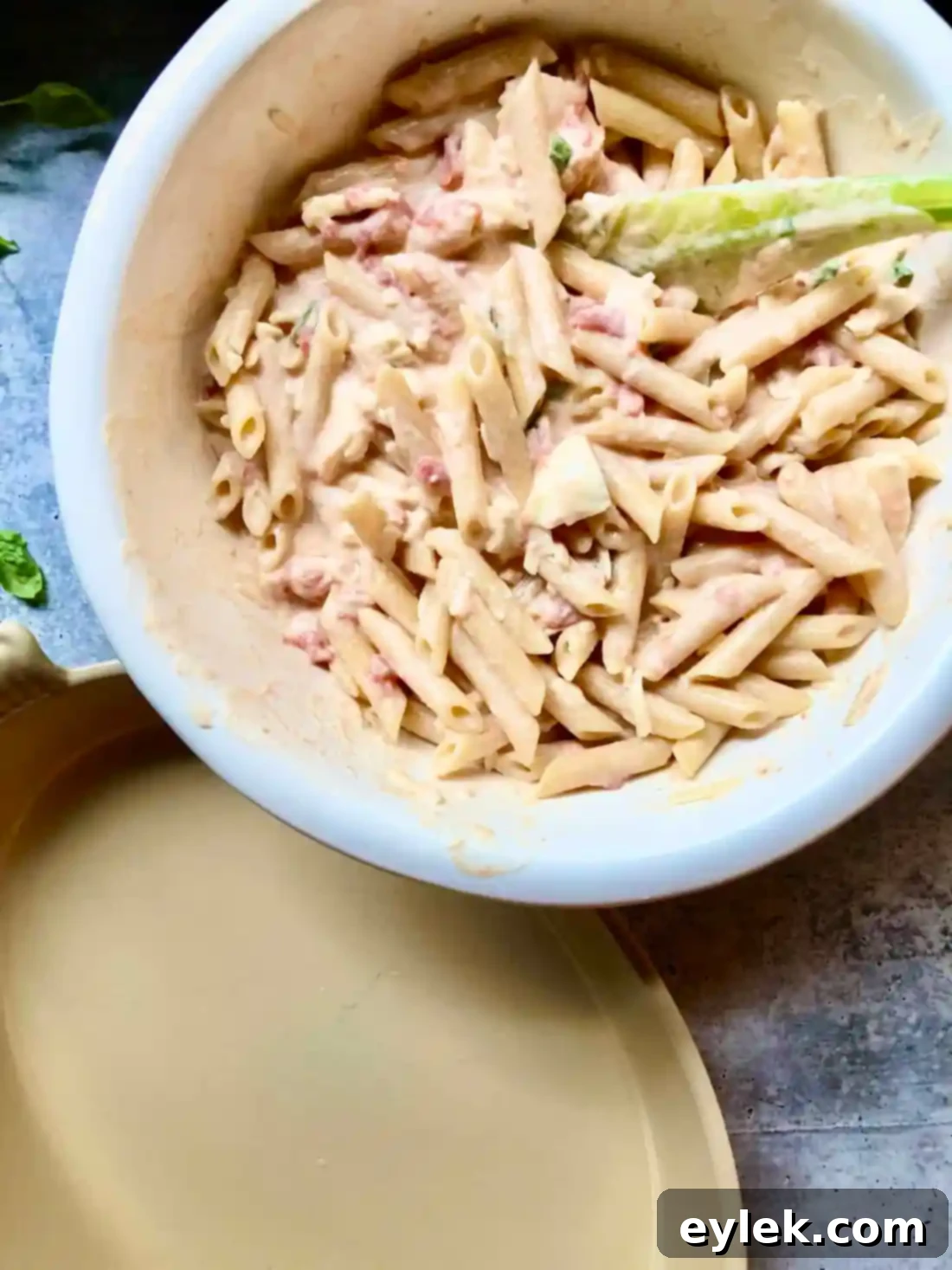 The Penne with Tomato, Cream & Five Cheeses, spread in a shallow baking dish and dotted with butter.