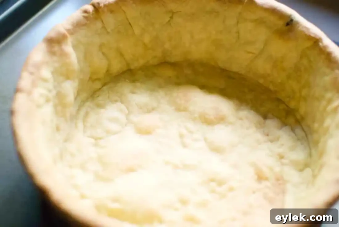The partially baked deep-dish pastry shell after removing foil, showing slight golden color.