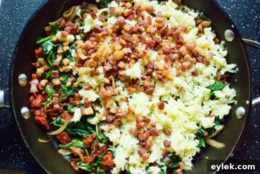 Spinach, sun-dried tomatoes, and other deep-dish quiche ingredients added to the skillet.