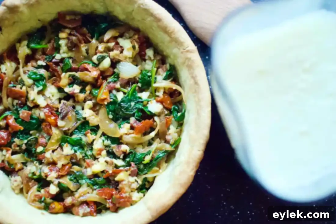 The assembled deep-dish spinach pancetta quiche, with filling and custard, ready for baking.