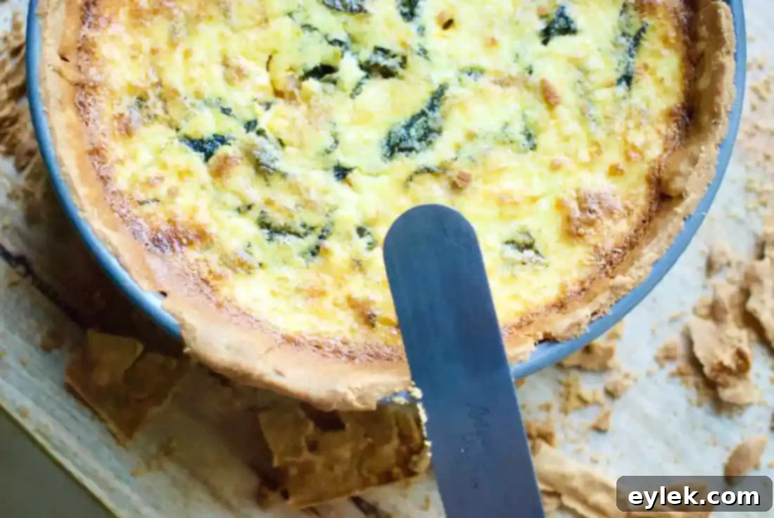 A close-up of a slice of the baked deep-dish spinach pancetta quiche, showcasing its layers.