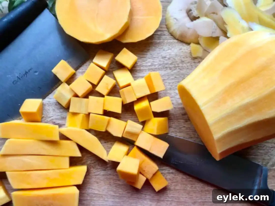 cubed butternut squash and diced onions on a baking sheet with olive oil