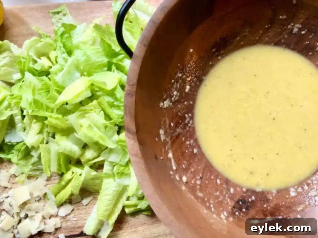 The fully emulsified and creamy homemade Caesar dressing in a wooden bowl, ready for tossing.