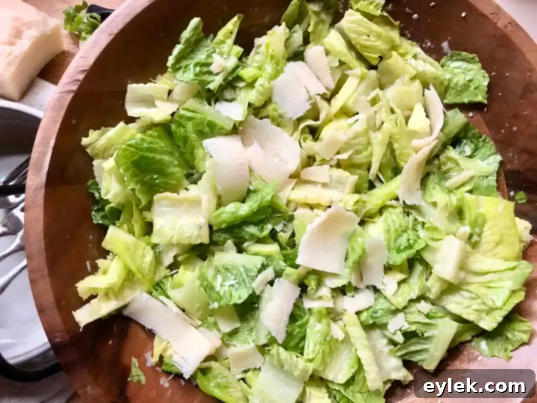 A beautifully plated Caesar salad, showcasing crisp romaine, creamy dressing, and generous shaved Parmesan.