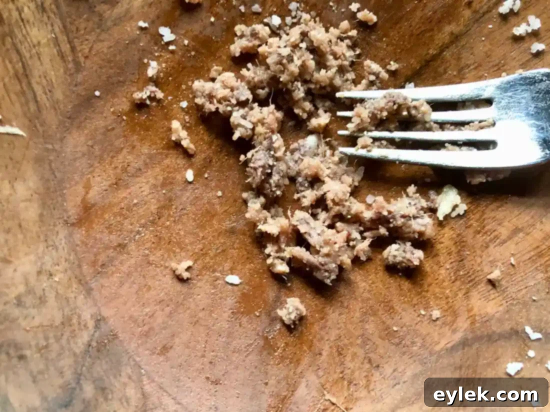 Ingredients for Caesar dressing - egg yolks, lemon juice, Dijon mustard, and Worcestershire sauce - added to a bowl.