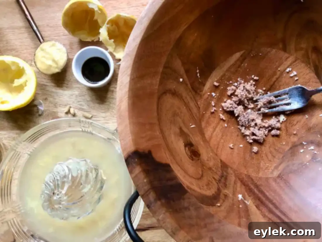 Vigorously whisking egg yolks, lemon juice, mustard, and Worcestershire in a wooden bowl for creamy Caesar dressing.
