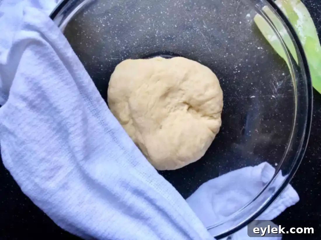 Smooth, kneaded dough in a bowl, covered with a damp towel.