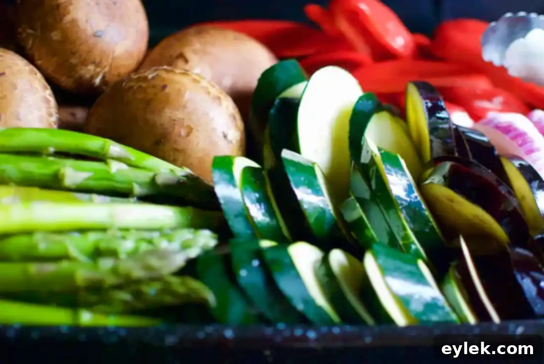 Assortment of prepped vegetables coated in olive oil and seasoning, ready for grilling.