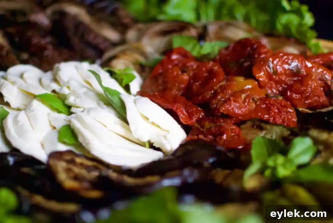 A large platter of artfully arranged crowd-pleasing grilled vegetables with added sun-dried tomatoes and fresh basil.